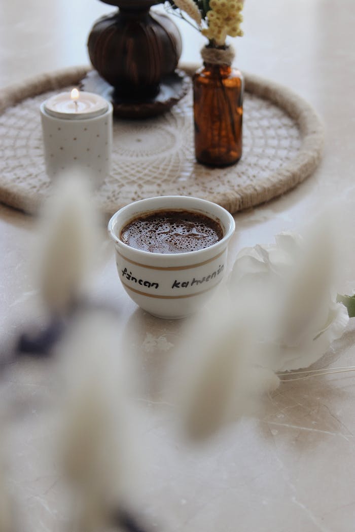 Warm cozy coffee scene with a candle and flowers for a peaceful ambiance.
