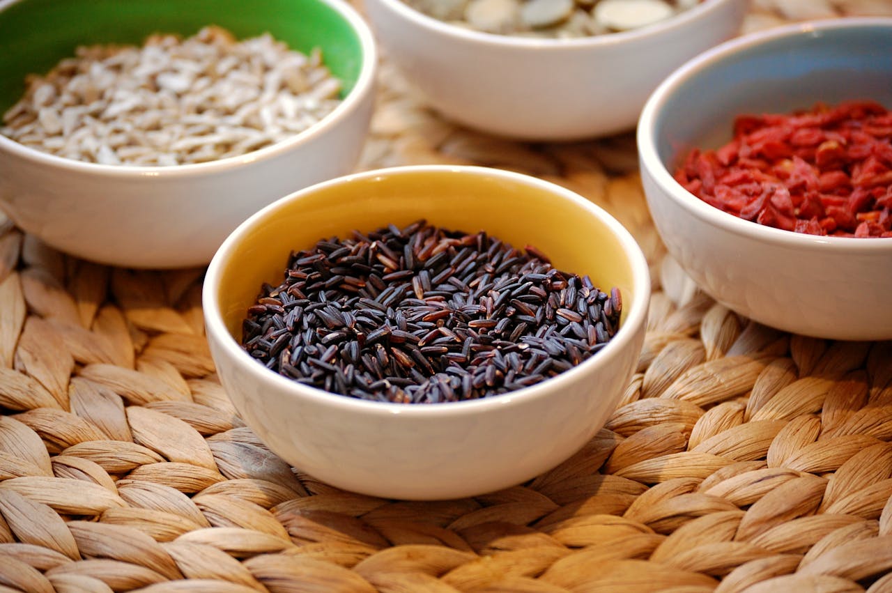 Close-up of black rice and assorted seeds in ceramic bowls. Perfect for healthy eating themes.